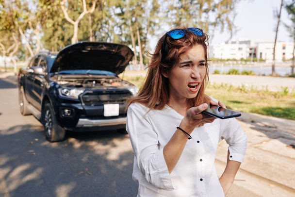 Emotional unhappy young woman recording voice message to friend or boyfriend after car accident - Photo, Image
