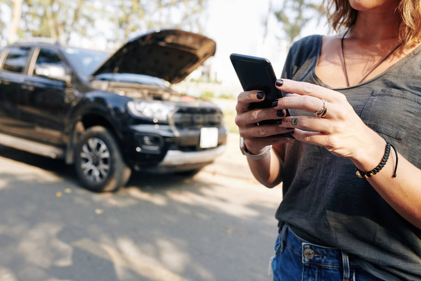 Przycięty obraz młodej kobiety korzystającej z aplikacji mobilnej do łączenia usług samochodowych - Zdjęcie, obraz