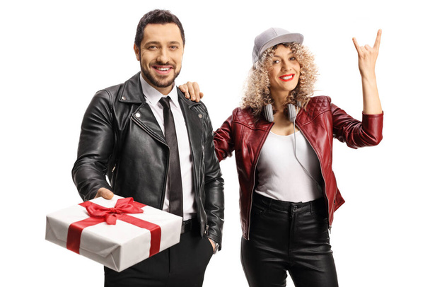 Cool young man and woman in leather jackets posing with a gift box isolated on white background - 写真・画像