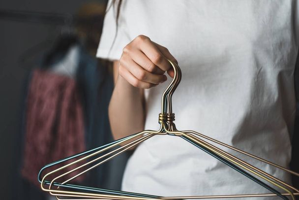 Woman holds metal clothes hangers in hands. - Foto, Bild