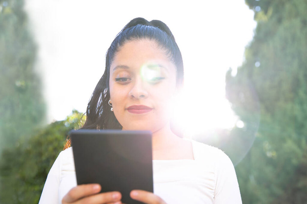 joven mujer latina leyendo un libro electrónico sobre el dispositivo de tableta digital. Concéntrate en el ebook
. - Foto, Imagen