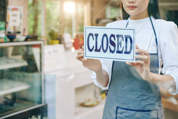 Sad female restaurant owner closing door and hanging sign - Photo, Image
