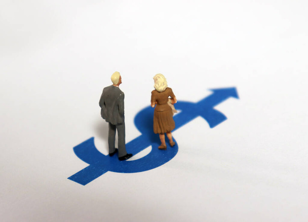 Um homem em miniatura e uma mulher em miniatura em pé no sinal do dólar
. - Foto, Imagem