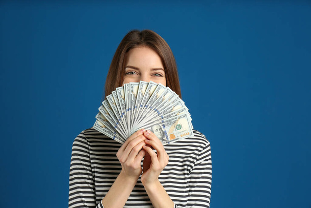 Young woman with cash money on blue background - Foto, afbeelding