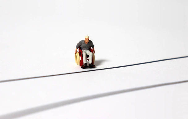 Un homme miniature en fauteuil roulant sur la route. - Photo, image