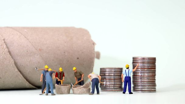 Miniatuur arbeiders werken en stapels munten. Begrip "minimumloonverbetering". - Foto, afbeelding