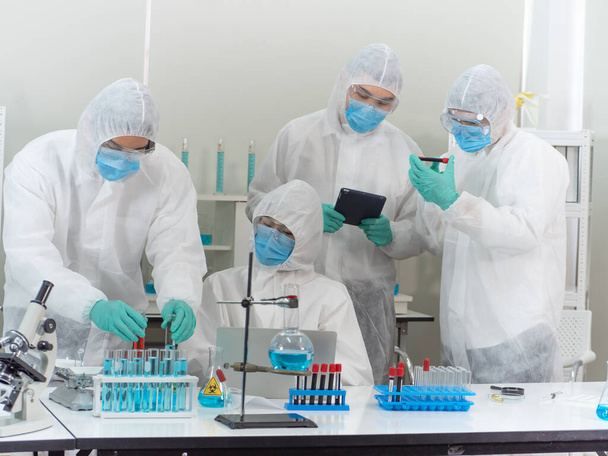 L'équipe scientifique asiatique en équipement de protection individuelle ou combinaison EPI est occupée à discuter du traitement du patient par le coronavirus. Concept infectieux pandémique. - Photo, image