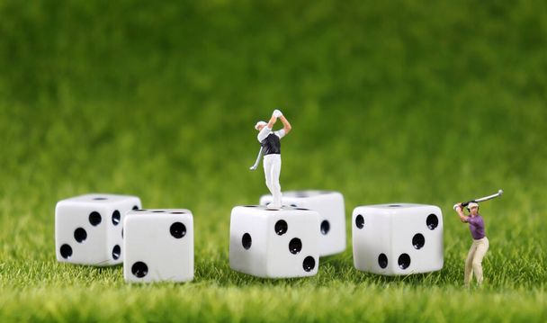 Два миниатюрных гольфиста и пять белых костей на заднем плане газона
. - Фото, изображение