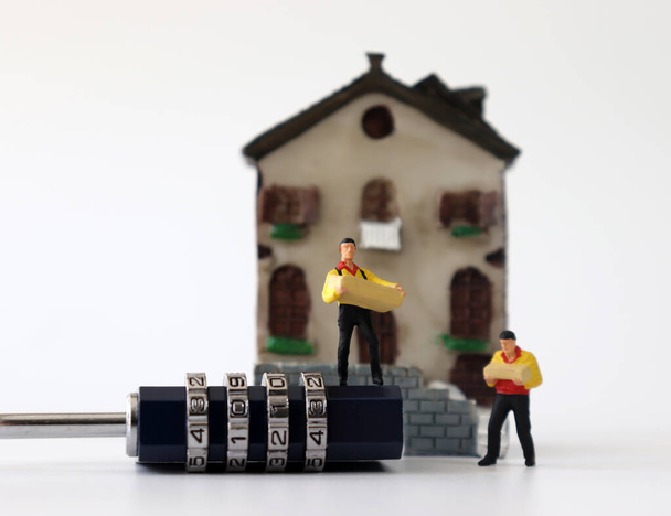 Mensajero en miniatura con cerradura delante de una casa en miniatura
. - Foto, Imagen