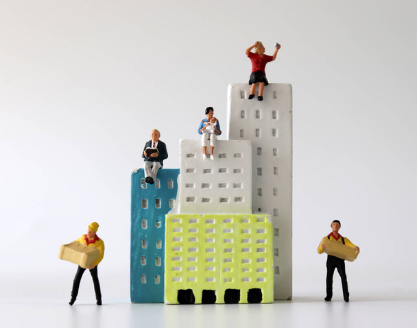 Personas en miniatura sentadas en un edificio en miniatura con mensajeros en miniatura
. - Foto, Imagen