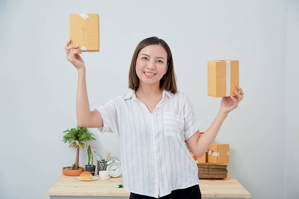 Asiática mujer mantenga paquete caja orden, trabajando en casa oficina. Entrega de marketing online, emprendedor de pymes startup o concepto freelance
 - Foto, Imagen