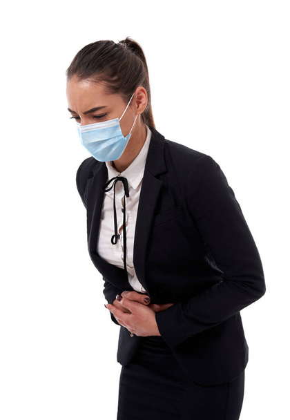 Hispanic businesswoman with sever abdominal pain, in face mask - Fotó, kép