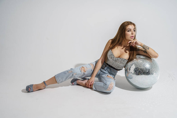 Stylish brunette with disco-ball posing at studio on gray background   - Foto, Bild