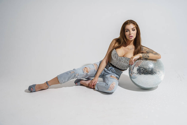 Stylish brunette with disco-ball posing at studio on gray background   - Фото, зображення