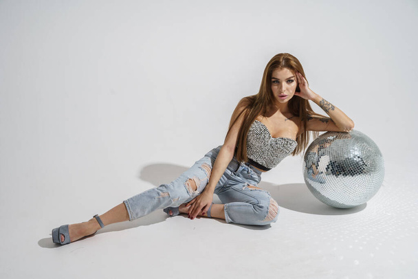 Stylish brunette with disco-ball posing at studio on gray background   - Foto, Bild
