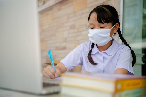 Junior Primary school girl Do homework at home Because the school is closed Due to the severe outbreak of the Corona virus Covid-19 and Dust PM2.5 in Bangkok Thailand - Foto, Bild