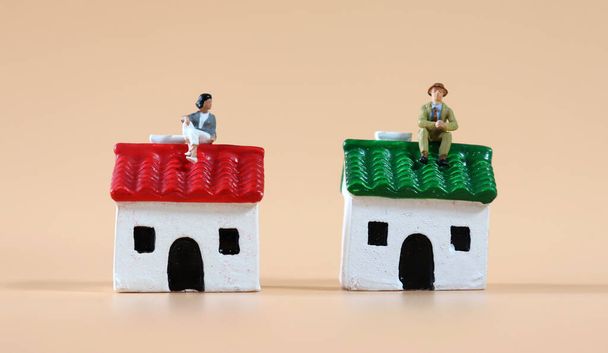 Les gens miniatures assis sur une maison miniature. - Photo, image