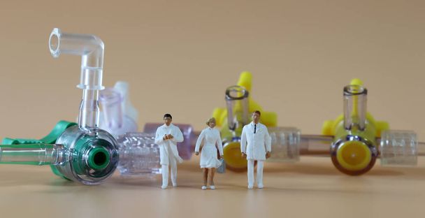 Médico en miniatura y enfermera de pie frente a una manguera médica
. - Foto, imagen