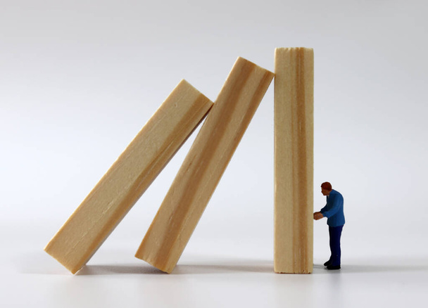 The concept of the economic crisis. Domino wooden blocks and a miniature people. - Photo, Image