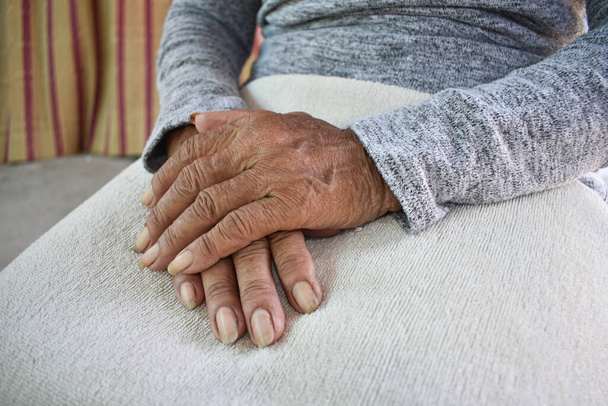 Die Hand der kranken alten Frau ruht auf dem Schoß. Psychische Betreuung zu Hause. - Foto, Bild