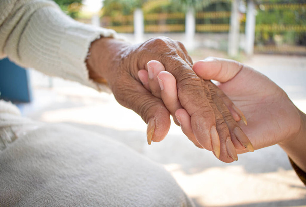 Enkelin aus nächster Nähe kümmert sich zu Hause um die kranke Großmutter, indem sie Händchen hält. Lebensstil unterstützt die Liebe zur Familie. - Foto, Bild