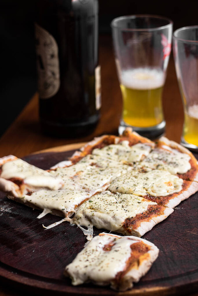 グラスとビールと自家製ピザのボトルと木製のレストランテーブル - 写真・画像