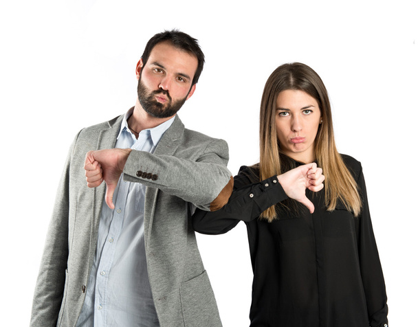 Couple with their thumbs down over white background - Photo, Image