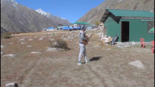Himalaya dağ vadisinde tek başına gitar çalan yalnız gezgin bir müzisyen ve gitar tellerinin sesi. Yaz müziği açık havada ilham verici bir ortam. Chitkul Himachal Hindistan. Ekim 2019 - Video, Çekim