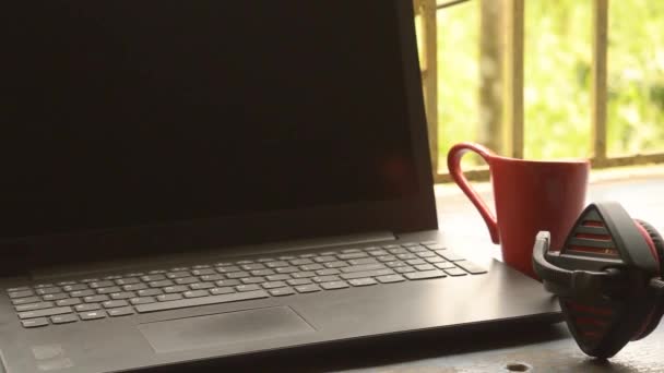Φορητά ακουστικά Binaural Sound USB με ακουστικά μικροφώνου για υπολογιστή, Skype τοποθετείται κοντά στο laptop στο φως του ήλιου παράθυρο το πρωί. Κόκκινο φλυτζάνι καφέ από απόσταση. Μείνετε στο σπίτι, Εργασία από το σπίτι, Απομακρυσμένη εργασία, Business Continuity background. - Πλάνα, βίντεο