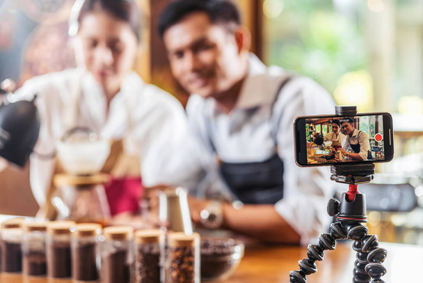 Telefon komórkowy biorąc wideo do dwóch azjatyckich Barista prezentując filiżankę kawy, kapanie pokaz kawy do publiczności w kawiarni, co espresso i americano, Właściciel małych firm i startup concep - Zdjęcie, obraz