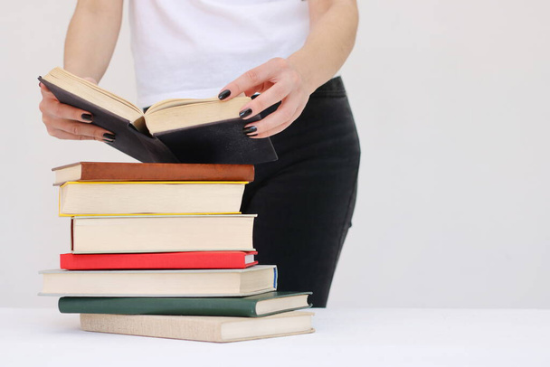 Μια όμορφη νεαρή μαθήτρια κρατά βιβλία στα χέρια της. - Φωτογραφία, εικόνα