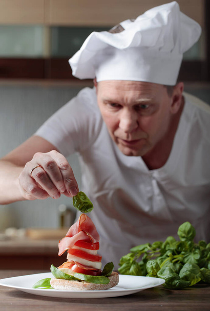 Chef prepares a snack with mozzarella, tomatoes and smoked meat . Selective focus . - Fotografie, Obrázek