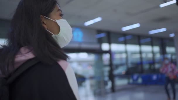 Junge gebräunte Asiatin mit Schutzmaske, die in der Warteschlange vor der Abflughalle des Flughafenterminals ansteht, von zu Hause aus reist, Covid-19-Pandemie, neue normale soziale Distanz, Zeitlupe  - Filmmaterial, Video