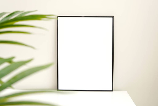 Zwarte frame mockup voor kunstwerken en groene palmbladeren, minimale, ascetische voorraad gestileerde foto. - Foto, afbeelding