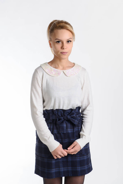 20-years blond girl in white blouse and blue skirt on white background thinking about something - Foto, Imagen