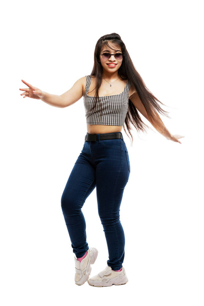 Laughing young girl in jeans. Brunette with long hair wearing sun glasses. Isolated on a white background. Vertical. Full height. - Fotó, kép