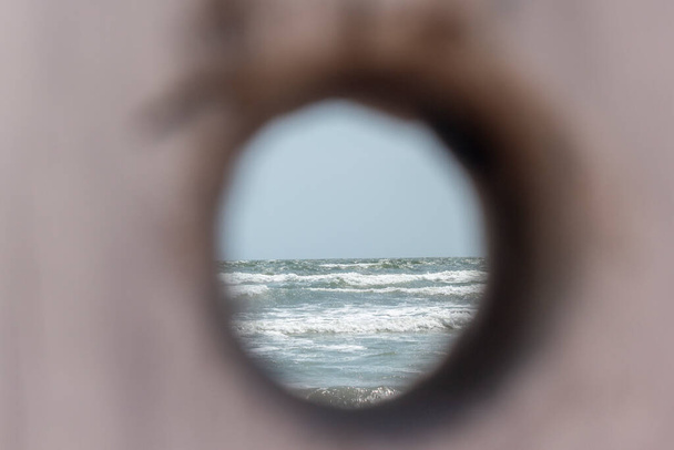 Mer avec des vagues vues à travers un trou sculpté tronc d'arbre ; au bord de la mer ; image concept - Photo, image