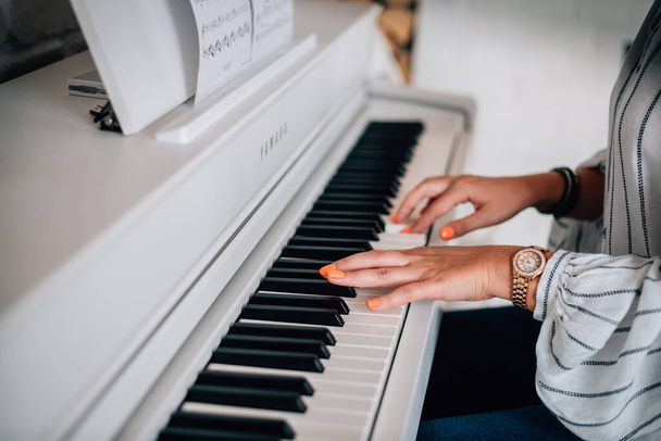 Frau mit heller Maniküre und Armbanduhr aus Holz spielt leichtes Klavier - Foto, Bild