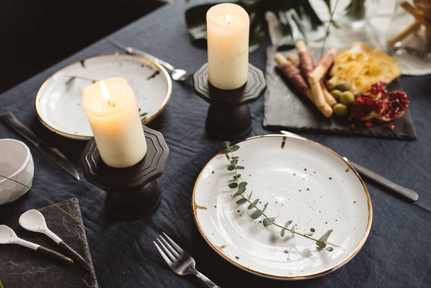 andles y platos para dos con citas de mesa en mesa negra
 - Foto, imagen
