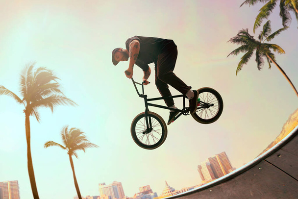 BMX rider wykonuje triki w skateparku o zachodzie słońca. - Zdjęcie, obraz