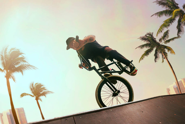 BMX-райдер исполняет трюки в скейтпарке на закате
. - Фото, изображение