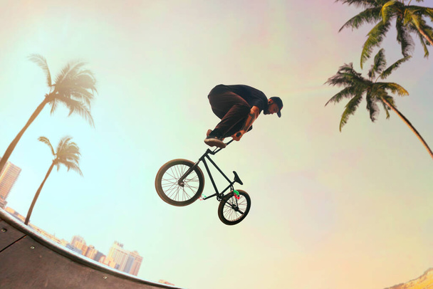 BMX rider is performing tricks in skatepark on sunset. - Photo, Image