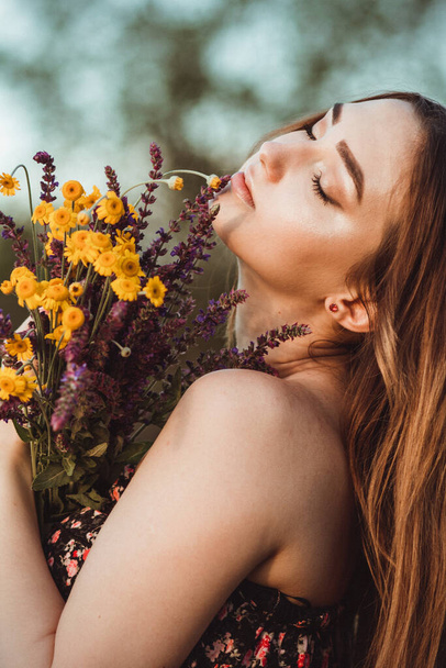 beautiful girl with bouquet of wildflowers on meadow, young woman with long hair in dress walking on nature,summer tender photo in village - Photo, image