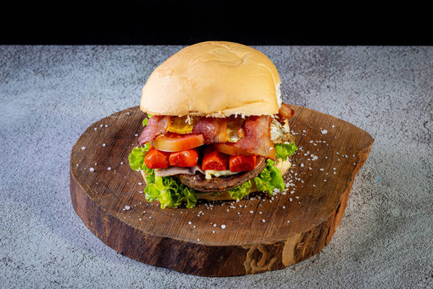 Wielki hamburger domowej roboty z burgerem wołowym, sałatą, pomidorem, kiełbasą, bekonem i serem, znany również jako X-tudo w Brazylii. - Zdjęcie, obraz