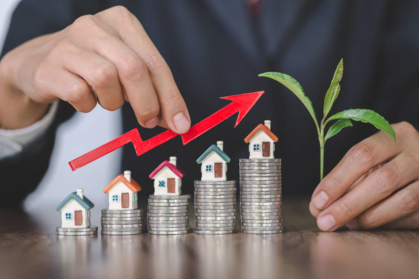 Wykres Holding Businessman nad rosnącą miniaturą domu, inwestycje w nieruchomości, finansowanie hipoteki inwestycyjnej i biznes kredytów mieszkaniowych, wzrost i pieniądze. - Zdjęcie, obraz