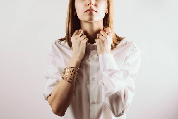Portrait of young adult woman holding collar of white shirt with her hands, selective focus - 写真・画像