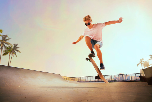 Skateboarder is performing tricks in skatepark on sunset. - Photo, Image