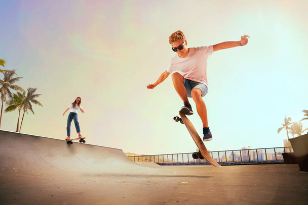 Скейтбордист виконує трюки в скейтпарку на заході сонця
. - Фото, зображення