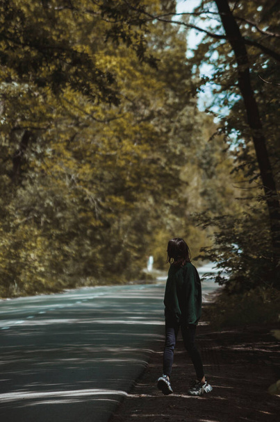 La chica camina sola cerca de un sendero forestal
. - Foto, Imagen