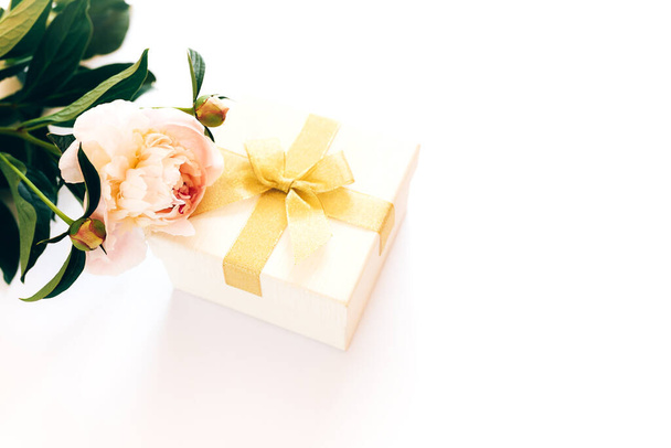 Прекрасный букет пионов и белая коробка с желтым бантом на белом фоне, цветущие пионы. - Фото, изображение